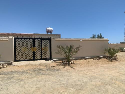 a building with a gate with a palm tree in front at Old Town House 4 in Ḑubā