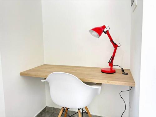 a desk with a red lamp and a white chair at Moderno Apto 2HA, Central con Wifi5G in Ibagué