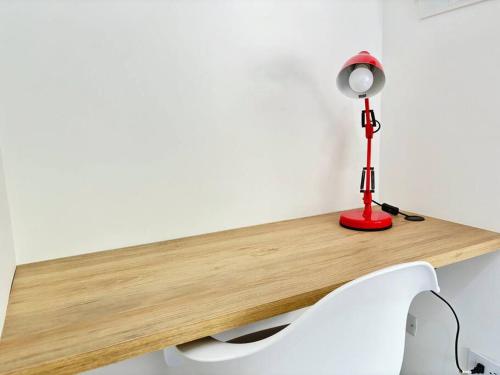 a desk with a red lamp and a white chair at Moderno Apto 2HA, Central con Wifi5G in Ibagué