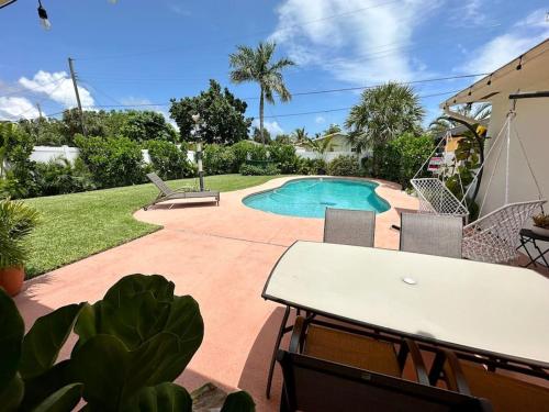 um pátio com uma mesa e uma piscina em Good Vibes House with private pool em Dania Beach