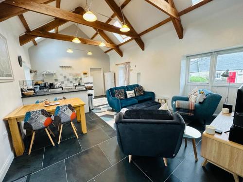 Una sala de estar con sillas azules y una mesa. en Trefechan Wen Barn, en Llanwnda