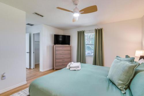 a bedroom with a green bed and a flat screen tv at Home with Screened Porch, Near Weeki Wachee Springs! in Spring Hill