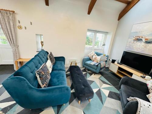 sala de estar con muebles azules y TV de pantalla plana en Trefechan Wen Barn, en Llanwnda