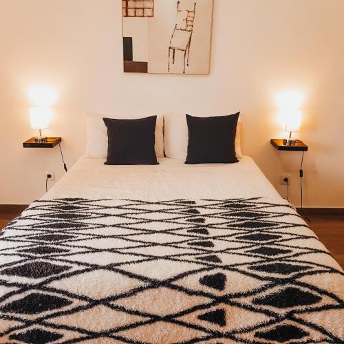 a bedroom with a black and white bed with two lamps at Quinta do Miradouro in Portalegre