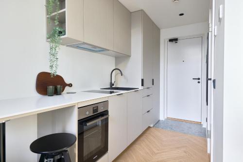 a kitchen with white cabinets and a sink and a stool at 21 Stylish Lofts by Dream Stay in Tallinn