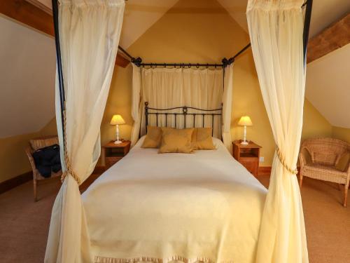 a bedroom with a large white bed with curtains at The Granary in Shrewsbury