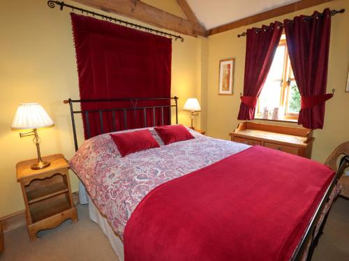 una camera da letto con un grande letto con una coperta rossa di The Old Dairy a Shrewsbury
