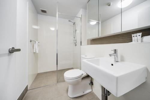 biała łazienka z toaletą i umywalką w obiekcie Spacious 2-Bed Conveniently by Lake Tuggeranong w mieście Tuggeranong