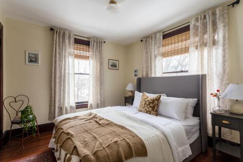 a bedroom with a bed and two windows at Bespoke 1920's Charm, Walk 2 Warren, & Hot Tub - The Spring House in Hudson