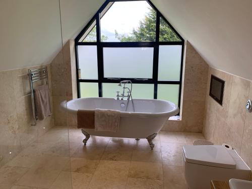 a large bathroom with a tub and a large window at Luxury 5-Bedroom Retreat in the Heart of Cheshire in Hale