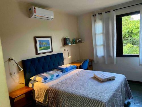 Vila Atlântica - House in Vilas do Atlântico في لورو دي فريتاس: غرفة نوم مع سرير مع اللوح الأمامي الأزرق ونافذة