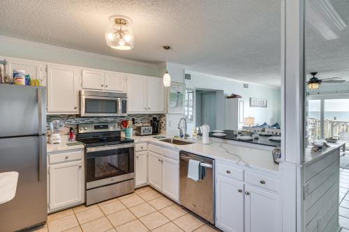 a kitchen with white cabinets and stainless steel appliances at Steps to the Beach Oceanfront Condo with Lanai! in North Topsail Beach