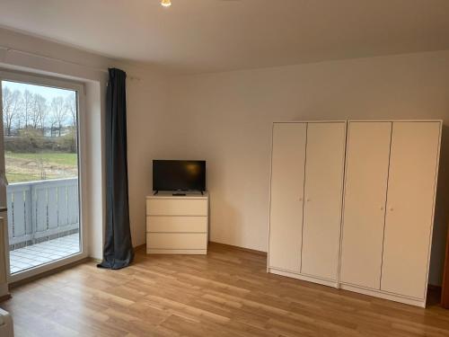 uma sala de estar com televisão, um armário e uma janela em Bavaria Home - Küche, Terrasse, 3 Schlafzimmer em Mainburg