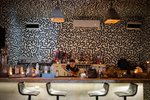 a bar with a man behind a counter with chairs at Casa Malca in Tulum