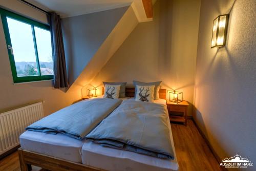 a bedroom with a bed with two lamps and a window at Auszeit-im-Harz Haus 5 Wohnung 36 in Stiege