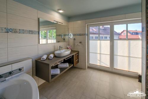 a bathroom with a sink and a mirror and a tub at Auszeit-im-Harz Haus 6 Ferienhaus in Wernigerode