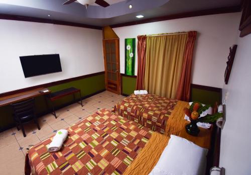 Habitación de hotel con 2 camas y TV de pantalla plana. en HOTEL LA RIVIERA, en Sabalito