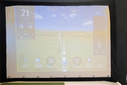 a television screen with a view of a field at Golf Sim & Putting Green - Rooftop with 360 Views in Scottsdale