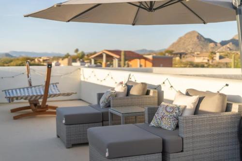 a patio with several couches and an umbrella at Golf Sim & Putting Green - Rooftop with 360 Views in Scottsdale