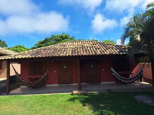 una casa roja con hamacas delante en Suítes e Flats das Papoulas Ferradura In Búzios, en Búzios