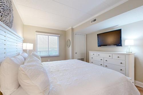 a bedroom with a white bed and a flat screen tv at Marigot Beach 1205 in Ocean City