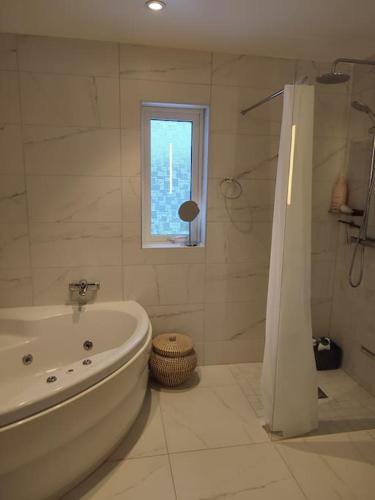 a white bathroom with a tub and a window at Göteborgs Pärla nr 2 in Gothenburg