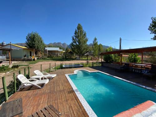 una piscina con 2 sillas y una terraza con en DOÑA ROSA CABAÑAS en Luján de Cuyo