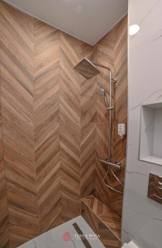 a shower in a bathroom with a wooden wall at Хотел Терра Роза in Karlovo