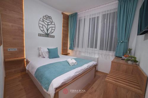 a bedroom with a bed and a window with blue curtains at Хотел Терра Роза in Karlovo