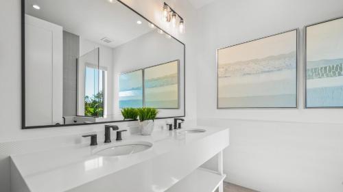 a white bathroom with two sinks and two mirrors at Shaker of Salt in Siesta Key