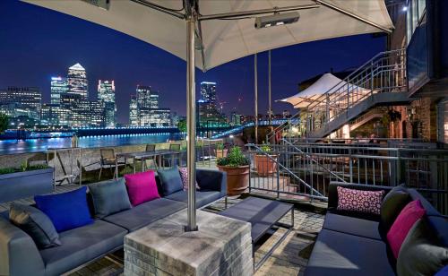um bar no último piso com um sofá e vista para a cidade em DoubleTree by Hilton London – Docklands Riverside em Londres