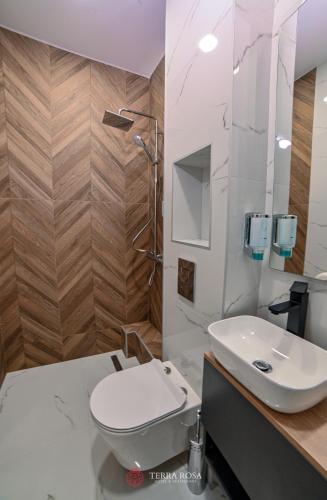 a bathroom with a white toilet and a sink at Хотел Терра Роза in Karlovo