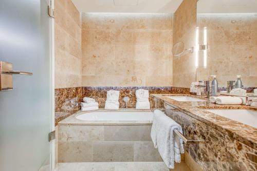 a bathroom with two sinks and a tub at Parkhotel Heilbronn in Heilbronn