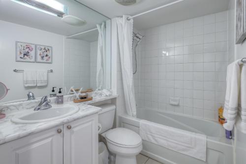 bagno bianco con servizi igienici e lavandino di RivetStays - The Yonge a Toronto