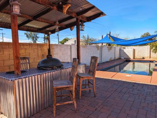 a patio with a grill and chairs and a swimming pool at Chic Parisian Guest House in Phoenix