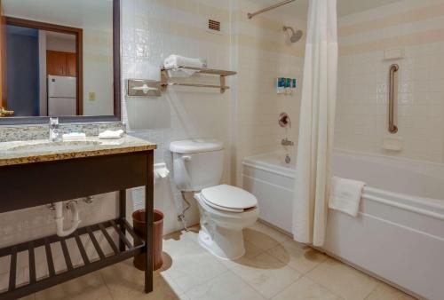 a bathroom with a toilet and a tub and a sink at Drury Inn & Suites Hayti Caruthersville in Hayti