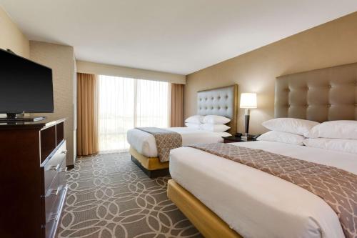 a hotel room with two beds and a flat screen tv at Drury Inn & Suites Dallas Frisco in Frisco
