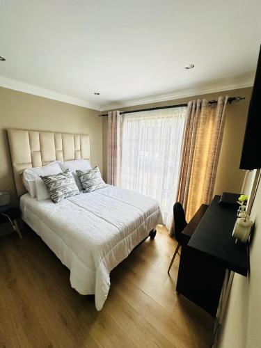 a bedroom with a bed and a desk and a window at Mayberry Heights in Alberton