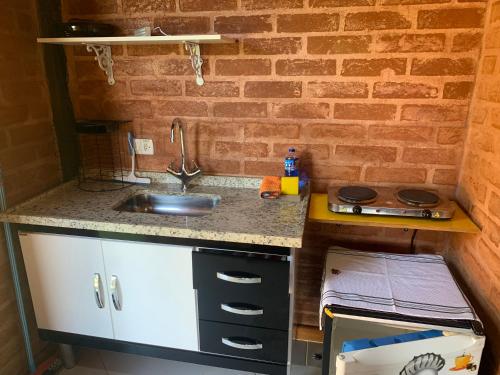 a kitchen with a sink and a brick wall at Chalés Roma in Santo Antônio do Pinhal