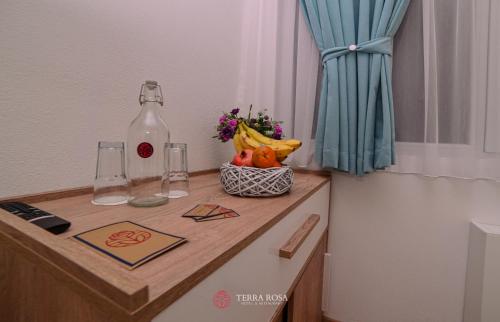 a table with a bottle and a bowl of fruit at Хотел Терра Роза in Karlovo