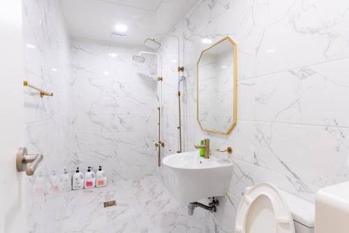 een witte badkamer met een wastafel en een spiegel bij The Wave Pension in Busan