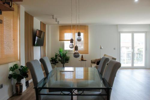 a dining room with a glass table and chairs at Villa Emérita in Vigo