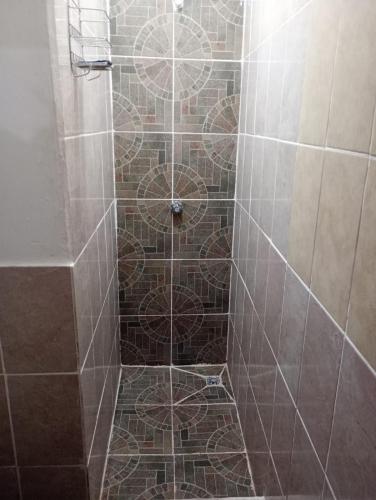a shower with a tiled floor with a door at Calm hostel in Antigua Guatemala