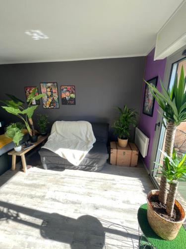 un salon avec un lit et des plantes en pot dans l'établissement tout pour VOTRE confort, au Lavandou