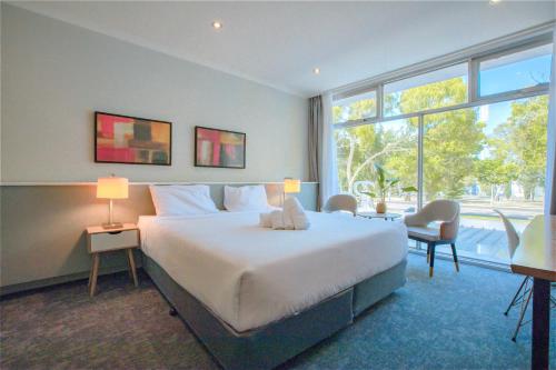 a bedroom with a large bed and a large window at The Parkmore Hotel in Melbourne