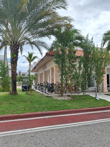蓬塔卡納的住宿－Apto estudio en Punta Cana, vista a la pisicina，棕榈树的房子和停在房子前面的自行车