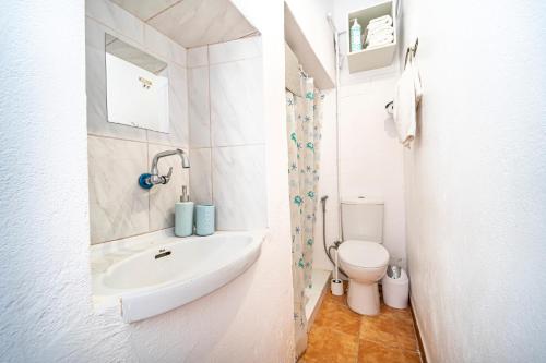 bagno bianco con lavandino e servizi igienici di Oasis Noalys a Sardina