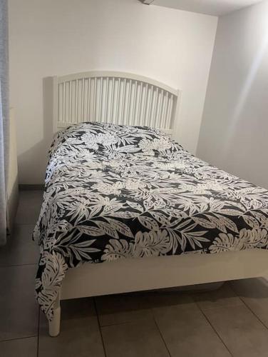 - un lit avec une couverture noire et blanche dans l'établissement Maison Téranga 2 Chambres Et 2 mezzanines et 2 parking gratuits, à Courrejean