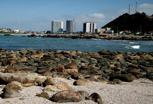 een groep rotsen op een strand bij het water bij Apartamento na Praia dos Sonhos Perto do Mar em Itanhaém in Itanhaém