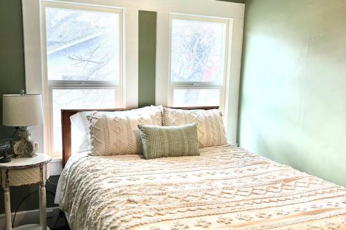 1 dormitorio con 1 cama con almohadas y 2 ventanas en The Vintage Daisy en Pocatello